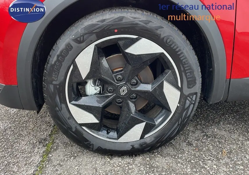 Gros plan sur la roue avant droite du Renault Captur rouge passion avec jante noire et argentée au design géométrique.