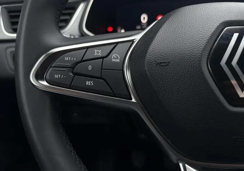 Gros plan sur la partie gauche du volant noir du Renault Captur 2025 avec commandes de régulateur et logo central.