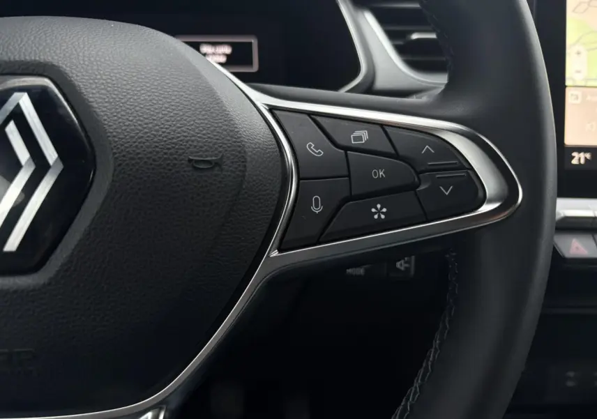 Gros plan sur la partie droite du volant noir du Renault Captur 2025 avec commandes multifonctions et écran tactile en arrière-plan.
