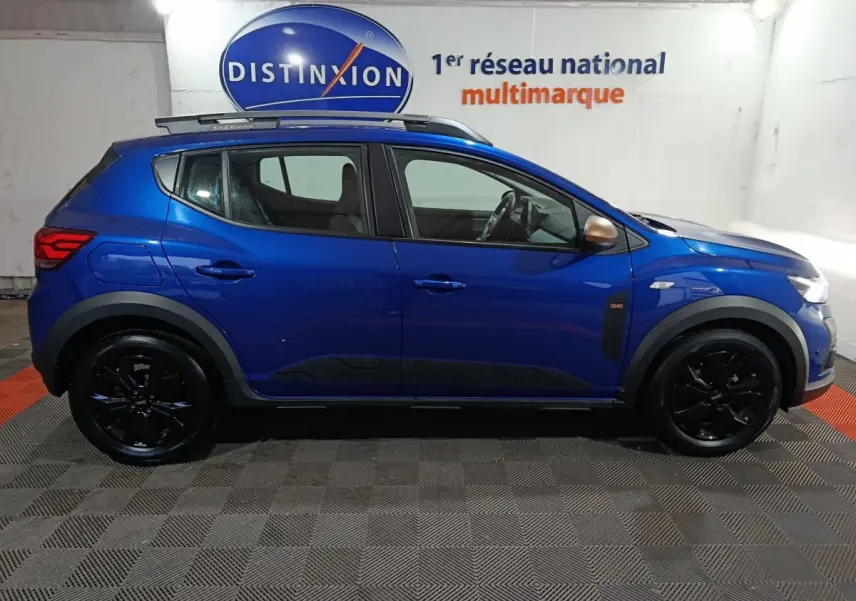 Vue profil droit d'une Dacia Sandero Extreme+ TCe 110 2024 bleu avec jantes noires et rails de toit assortis.