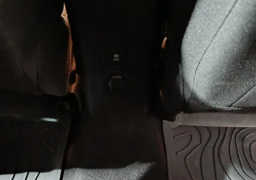 Vue rapprochée de la prise 12V et port USB entre les sièges arrière noirs du Dacia Sandero Extreme+ bleu.