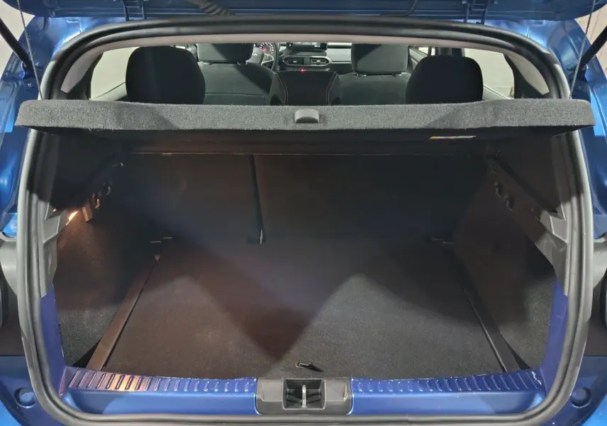 Coffre ouvert vu de l'arrière d'une Dacia Sandero Extreme+ TCe 110 bleu 2024, avec tablette cache-bagages.