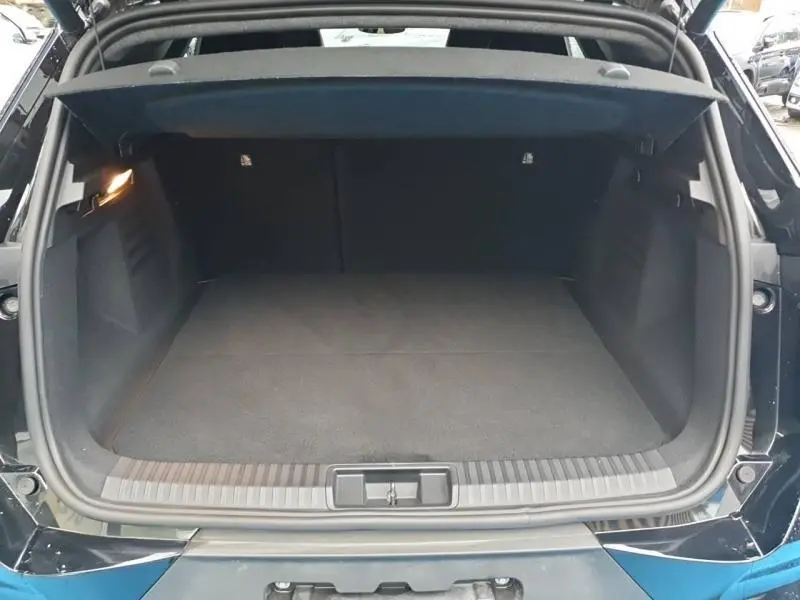 Coffre ouvert vu de l'arrière d'une Renault SYMBIOZ noir étoilé, espace de chargement vide et éclairage intérieur allumé.