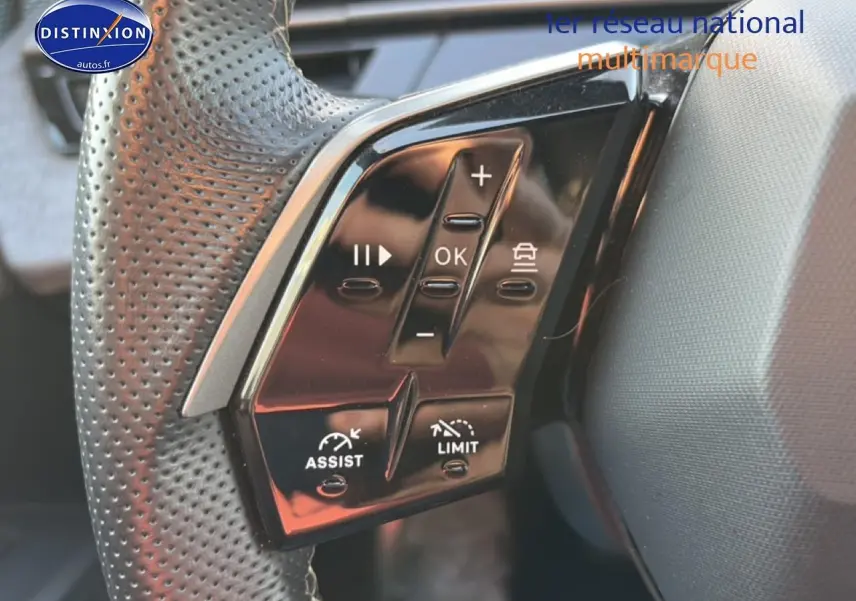 Gros plan sur les commandes multifonctions noires du volant cuir perforé côté gauche du Peugeot 3008 gris 2025.
