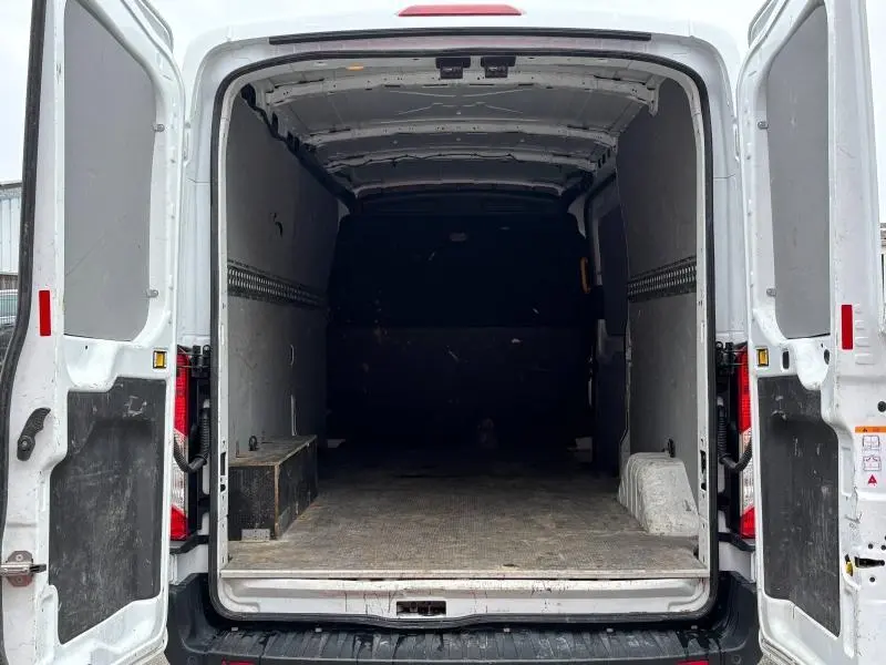Vue arrière ouverte du fourgon Ford Transit blanc Glacier montrant l'espace de chargement vide et la double porte battante ouverte.