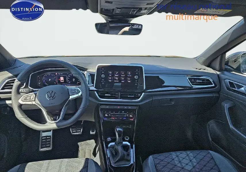 Intérieur avant du Volkswagen T-Roc noir perle 2025 avec tableau de bord numérique et volant multifonction sport.