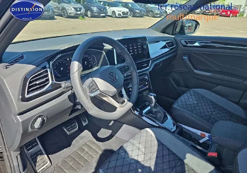 Intérieur noir du Volkswagen T-Roc 2025, vue côté conducteur avec volant cuir multifonction et console centrale moderne.