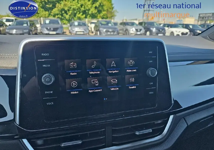 Écran tactile central du tableau de bord du Volkswagen T-Roc noir perle, avec menus radio et navigation visibles.