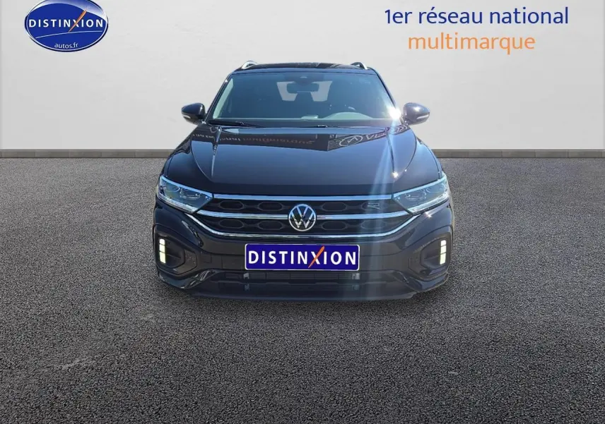 Volkswagen T-Roc noir perle vu de face avec calandre R-Line et feux LED allumés sur fond neutre.