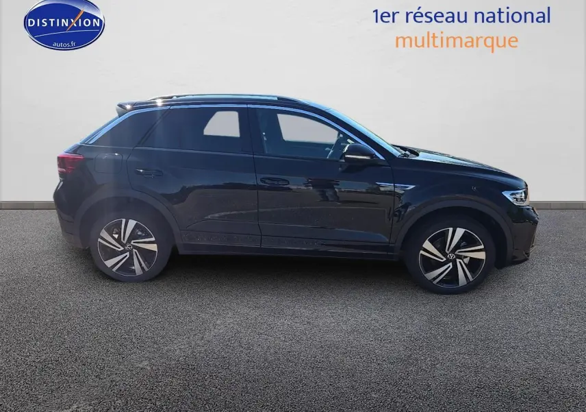 Profil côté gauche d'un Volkswagen T-Roc noir perle 2025 finition R-Line avec jantes alliage et barres de toit argentées.