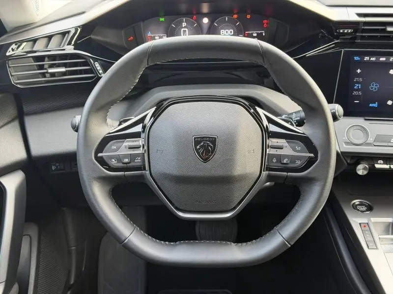 Vue rapprochée du volant multifonction noir du Peugeot 308 2024 avec tableau de bord numérique et écran tactile.