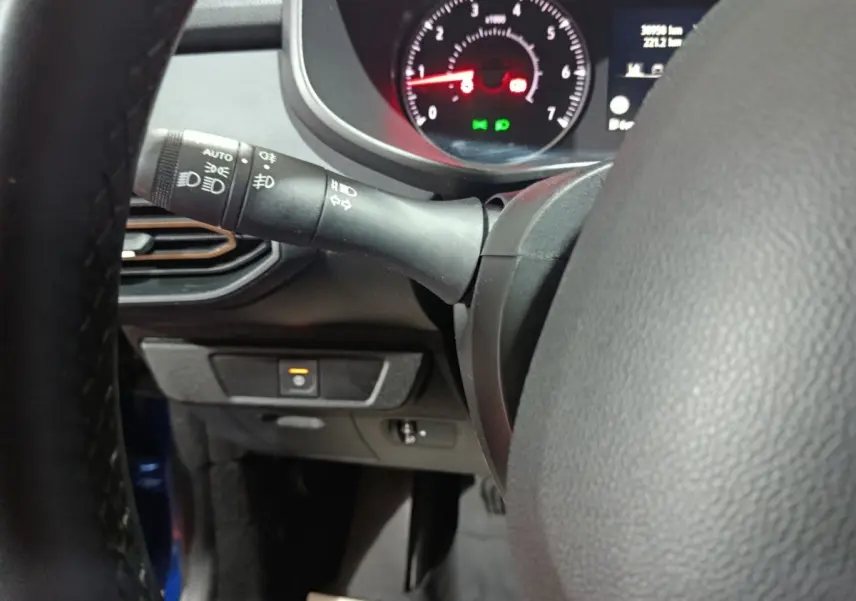 Gros plan sur le volant cuir synthétique et la manette des phares d’une Dacia Sandero Extreme+ TCe 110 2024 bleu.