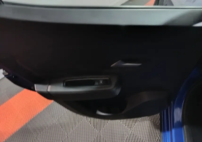 Vue rapprochée de la porte avant gauche bleu foncé de la Dacia Sandero Extreme+ TCe 110 avec poignée intérieure noire.