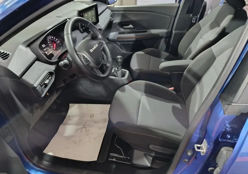 Vue intérieure côté conducteur de la Dacia Sandero Extreme+ TCe 110 2024 avec volant cuir et boîte manuelle, sièges gris.