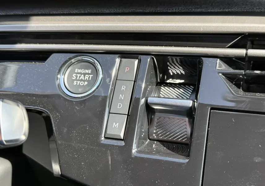 Gros plan sur la console centrale noire brillante du Peugeot 3008 Hybrid 145 Allure avec bouton start/stop et commandes de boîte auto.
