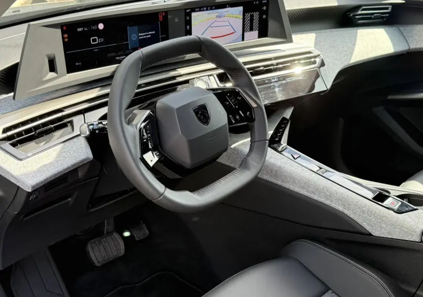 Intérieur du Peugeot 3008 Hybrid 145 e-DSC6 Allure 2025, vue du poste de conduite avec volant compact et double écran panoramique.