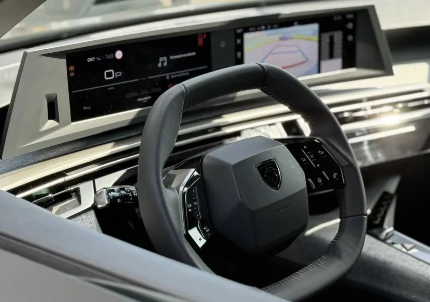 Vue intérieure rapprochée du volant cuir noir et du tableau de bord numérique du Peugeot 3008 Hybrid 2025.