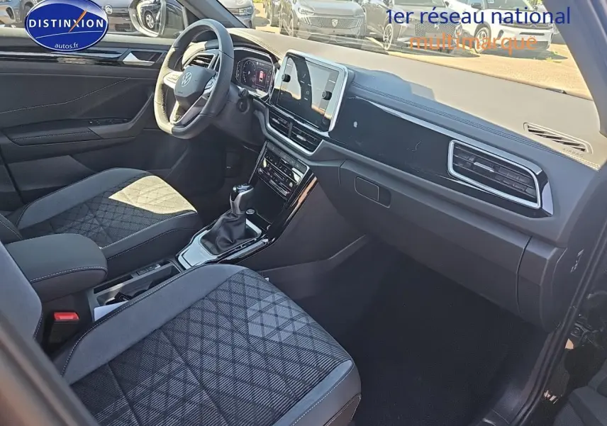 Intérieur du Volkswagen T-Roc 2025 noir perle, vue côté passager mettant en valeur les sièges tissu et le tableau de bord moderne.