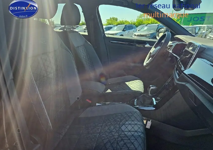 Intérieur avant droit du Volkswagen T-Roc noir perle, sièges tissu R-Line avec surpiqûres et tableau de bord moderne.