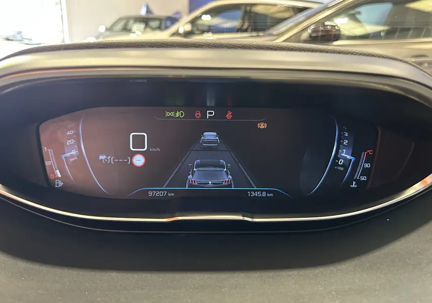 Affichage numérique du tableau de bord du Peugeot 5008 gris, montrant la vitesse à zéro et les alertes actives.