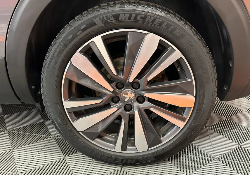Gros plan sur la jante alliage bicolore et pneu Michelin d'un Peugeot 5008 gris, côté arrière droit.
