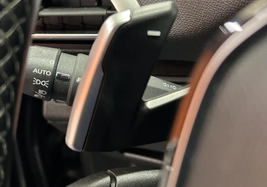 Gros plan sur la palette de changement de vitesses et le commodo d'éclairage du Peugeot 5008 gris, intérieur conducteur.