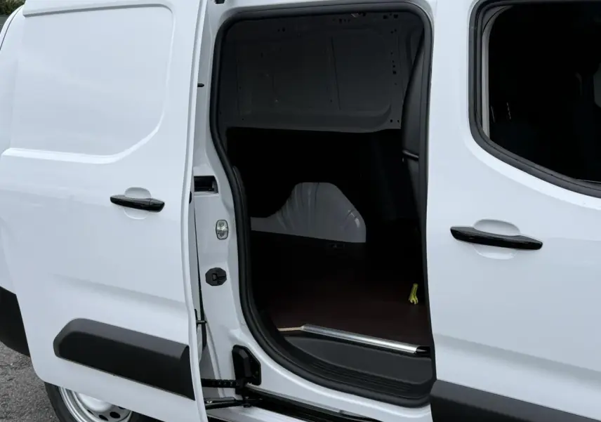 Vue latérale droite du Peugeot Partner blanc 2025 avec porte coulissante ouverte montrant l'espace de chargement vide.