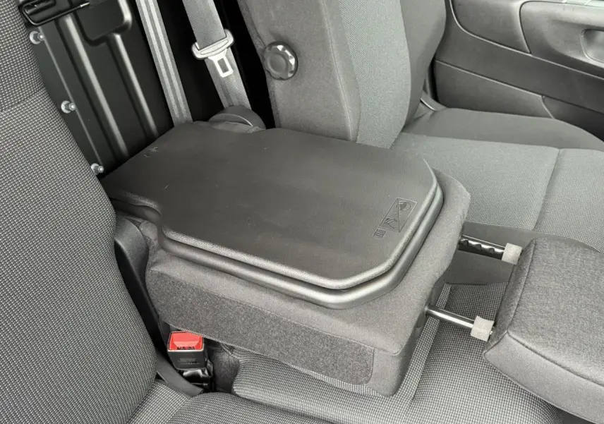 Détail intérieur montrant la banquette centrale rabattue avec tablette écritoire dans un Peugeot Partner XL blanc.