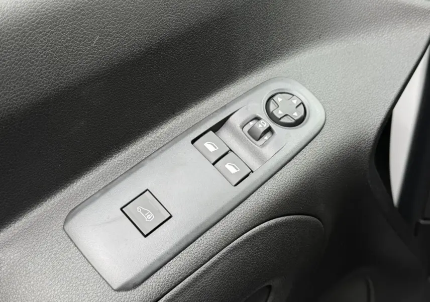 Gros plan sur les commandes de lève-vitres et réglage des rétroviseurs côté conducteur d'un Peugeot Partner blanc.