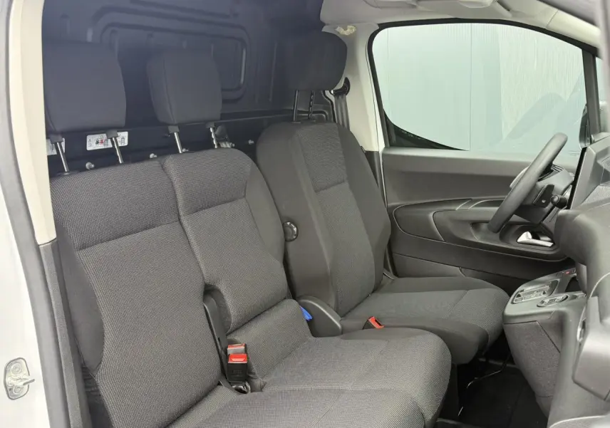 Vue intérieure côté conducteur du Peugeot Partner XL 2025 blanc, montrant la banquette 3 places en tissu gris foncé.