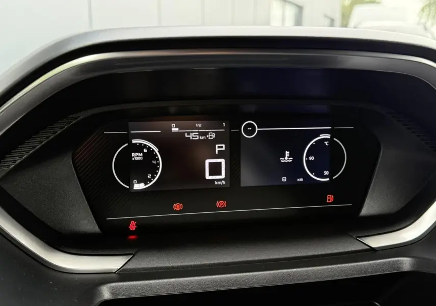 Tableau de bord numérique du Peugeot Partner 2025, affichant vitesse zéro et compte-tours, vue frontale rapprochée.