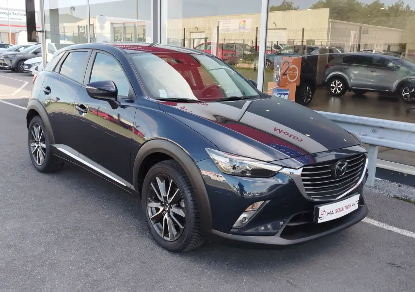 Mazda CX-3 2016 bleu Dynamic Blue Mica en 3/4 avant droit, avec jantes alliage et calandre chromée.