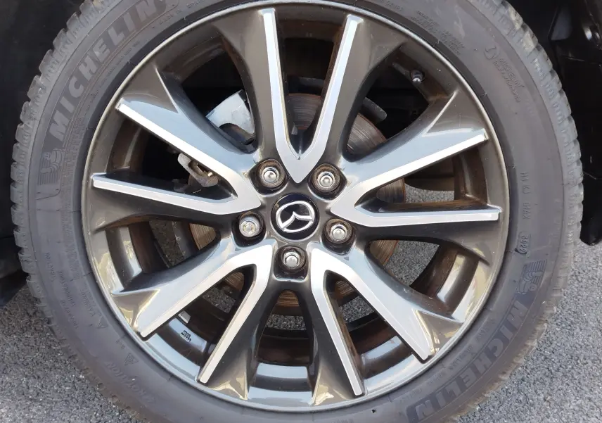 Gros plan sur la jante alliage gris foncé à 10 branches du Mazda CX-3 Dynamic Blue Mica de 2016 avec pneu Michelin.