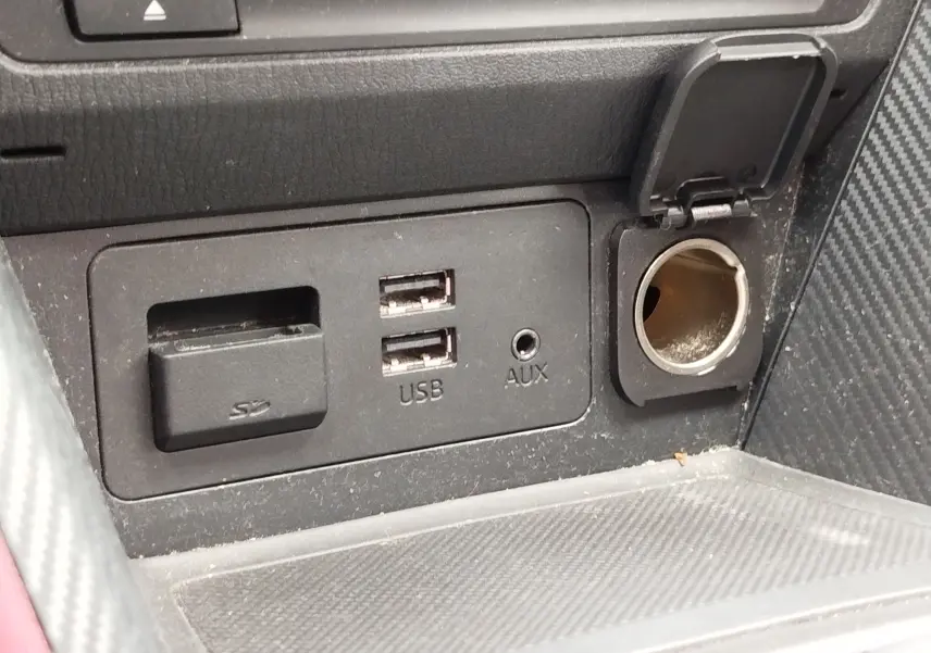 Gros plan sur la console centrale du Mazda CX-3 2016 montrant les ports USB, SD et prise 12V avec couvercle ouvert.