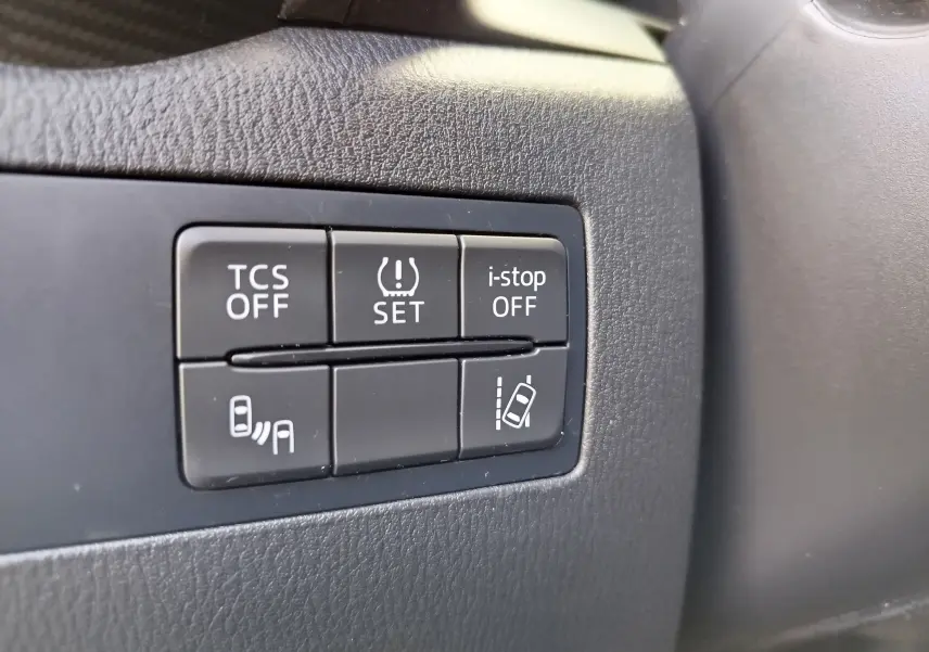 Gros plan sur les boutons de contrôle d'assistance à la conduite dans le tableau de bord noir du Mazda CX-3 2016.