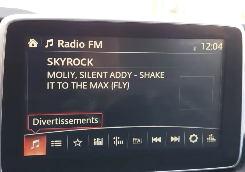 Écran central du système multimédia du Mazda CX-3 affichant la radio FM sur la station Skyrock à 12h04
