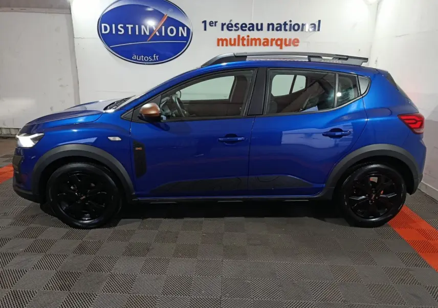Profil droit d'une Dacia Sandero Extreme+ TCe 110 bleu avec jantes noires et rétroviseurs couleur bronze.
