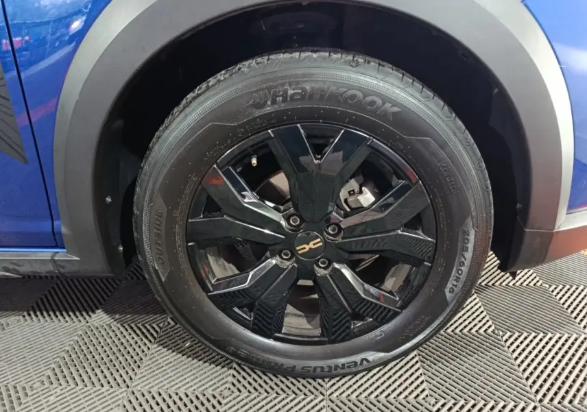 Gros plan sur la roue avant gauche noire brillante d'une Dacia Sandero Extreme+ bleu 2024.