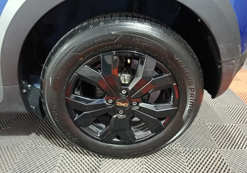 Gros plan sur la roue avant droite noire brillante de la Dacia Sandero Extreme+ bleu 2024 avec jante design.