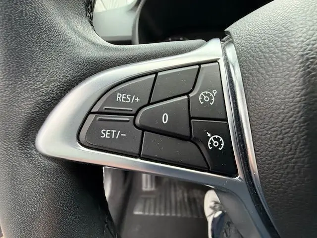 Gros plan sur les commandes de régulateur de vitesse au volant d’un Dacia Sandero blanc glacier 2023.