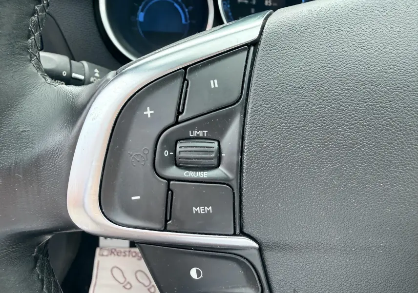 Gros plan sur les commandes de régulateur de vitesse au volant d’une Citroën DS4 noire de 2012.