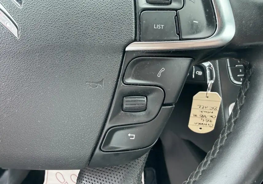 Gros plan sur les commandes du volant côté gauche d’une Citroën DS4 noire, avec touches de téléphonie et de menu.