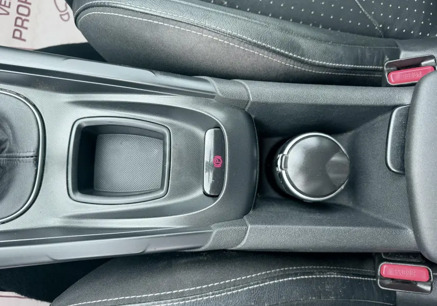 Vue plongeante sur la console centrale noire du Citroën DS4, avec frein à main électrique et porte-gobelet.