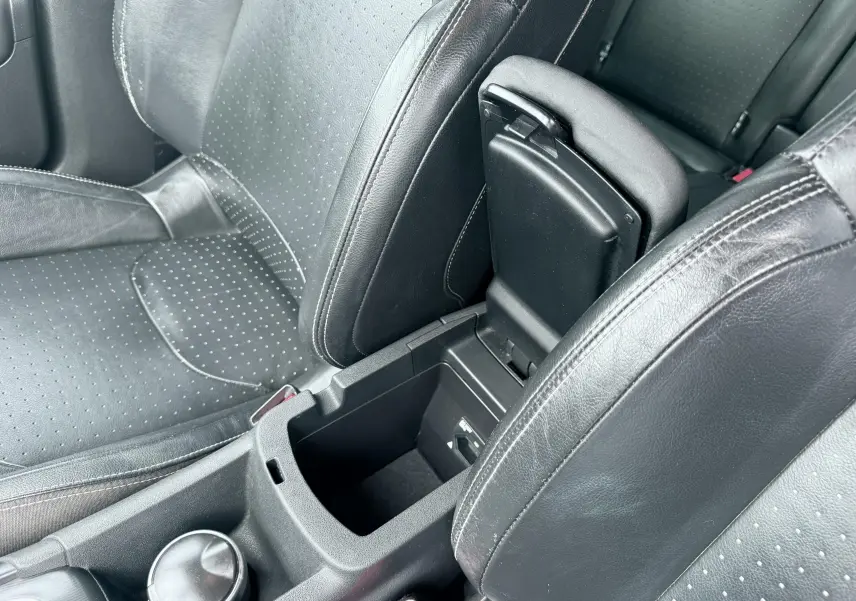 Vue rapprochée de l’intérieur noir en cuir perforé du Citroën DS4, avec accoudoir central ouvert et console visible.