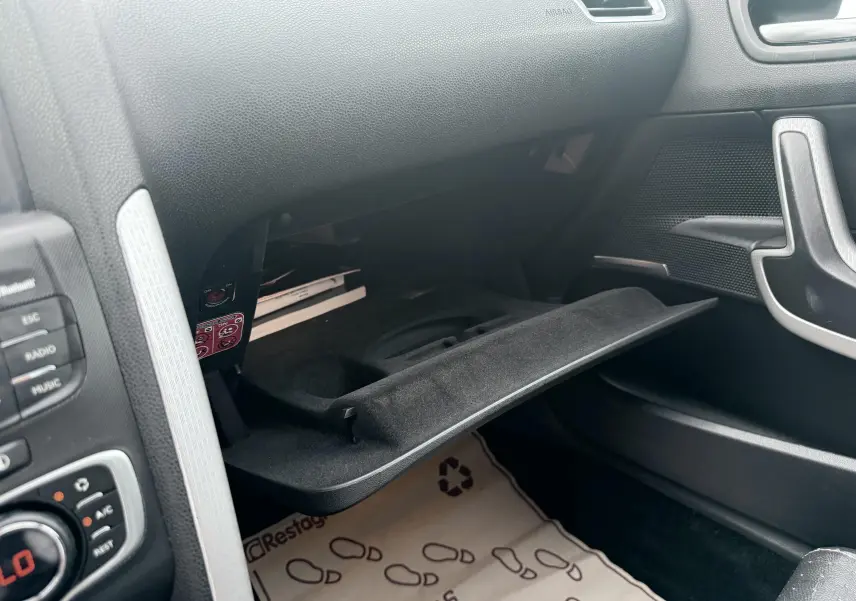 Vue intérieure côté passager du coffre à gants ouvert d'une Citroën DS4 noire de 2012, avec plancher protégé par tapis.