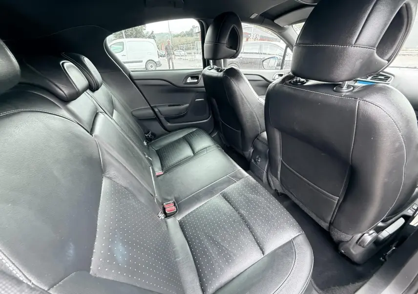 Vue intérieure arrière de la Citroën DS4 2012, sièges en cuir noir et finition perforée, ambiance sobre et élégante.