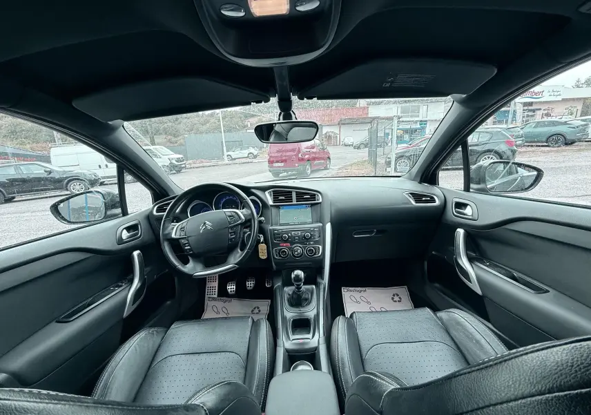 Vue intérieure avant de la Citroën DS4 noire, montrant le tableau de bord, volant cuir et console centrale avec boîte manuelle.