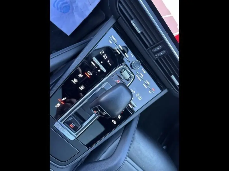 Vue rapprochée de la console centrale noire brillante du Porsche Cayenne Coupe 3.0 V6 340CV avec levier de vitesse automatique.