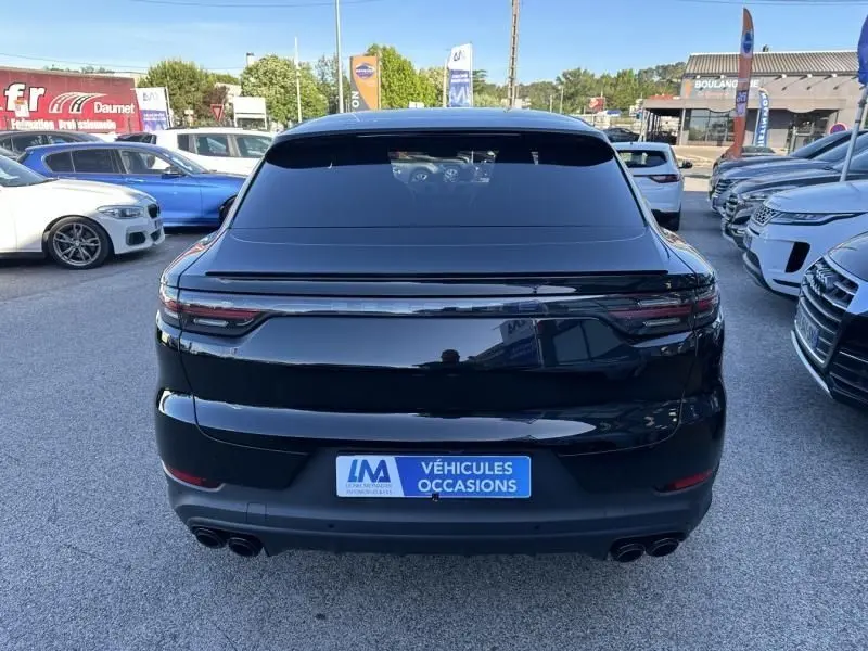 Vue arrière d'un Porsche Cayenne Coupé noir métal de 2020 avec feux reliés et double sortie d'échappement.