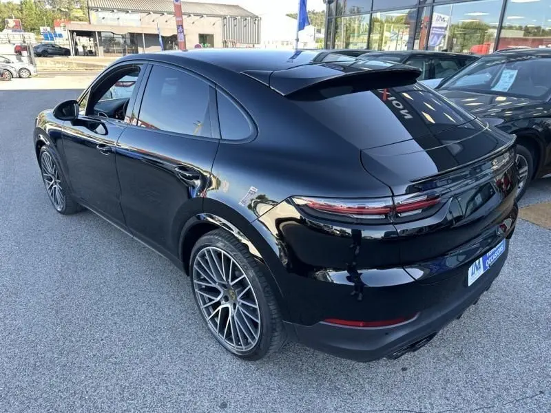 Vue 3/4 arrière droite d'un Porsche Cayenne Coupe 2020 noir métal avec jantes sport et toit ouvrant fermé.